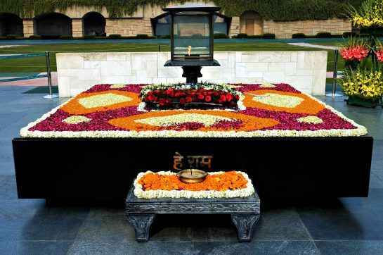 "Raj Ghat in Delhi, a serene memorial dedicated to Mahatma Gandhi, featuring a simple black marble platform surrounded by lush gardens.